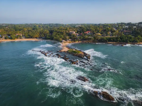 Malownicze wybrzeże, gdzie leży Sri Lanka. Tropikalna roślinność, plaże i skaliste wysepki w turkusowej wodzie.
